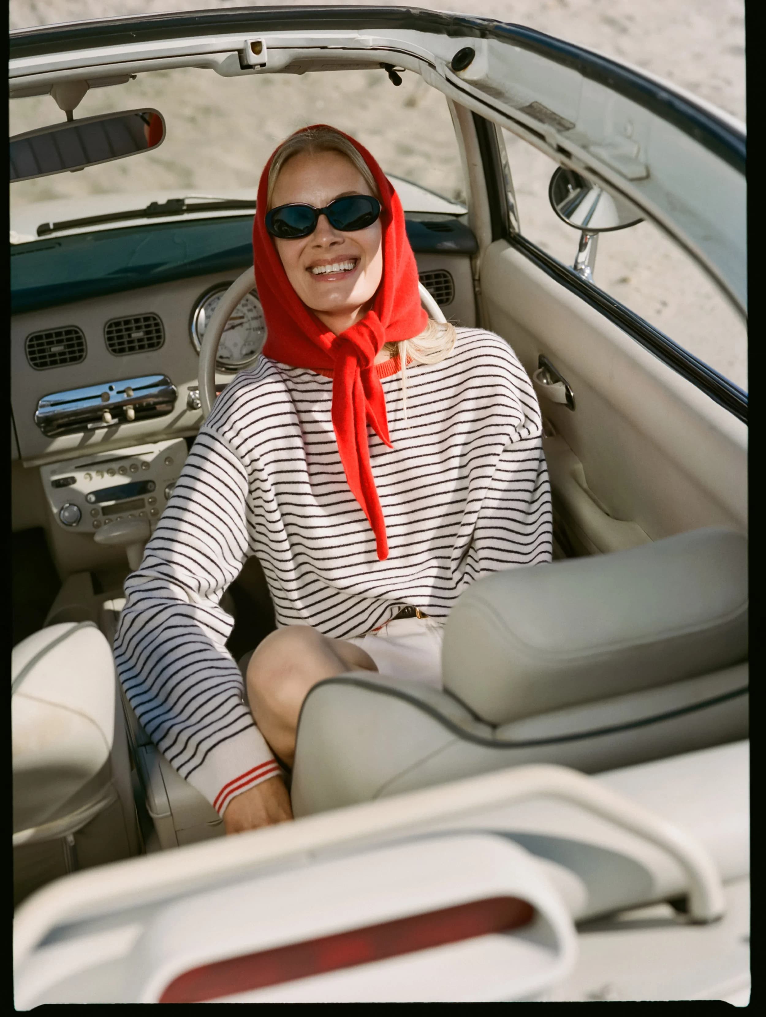 Model in a soft white and deep navy striped cashmere crewneck with a tomato red neckerchief.