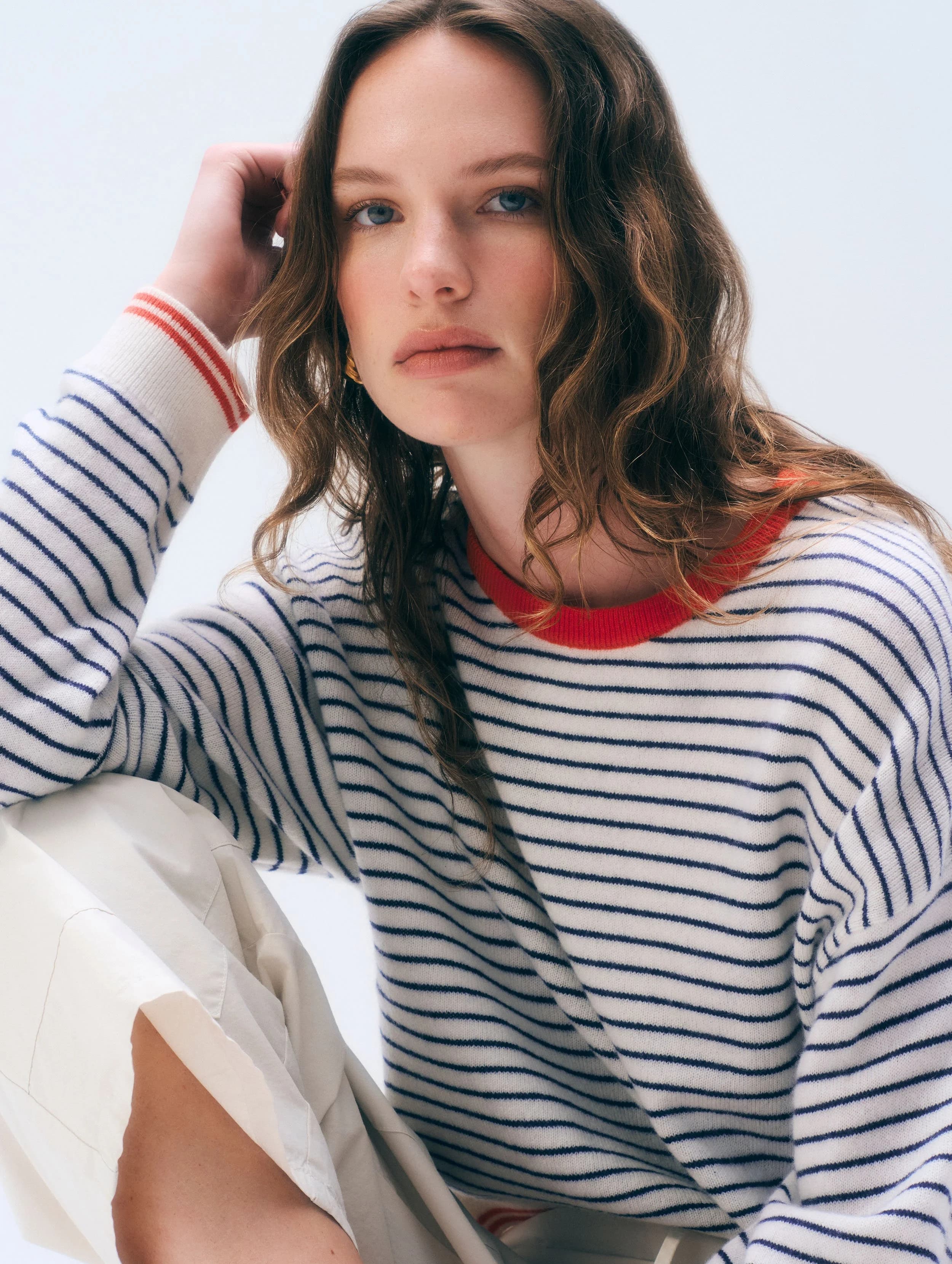 Model in a white, navy and red striped cashmere crewneck.
